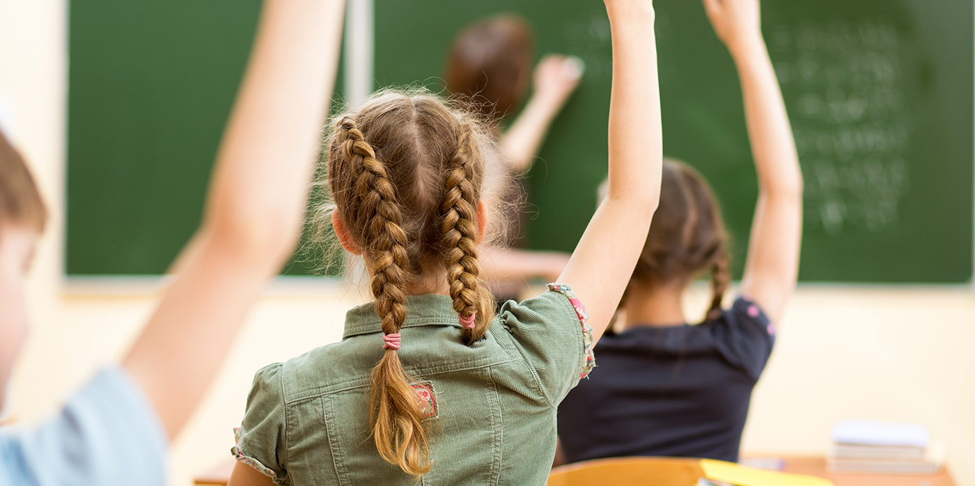 Girl with hand up in classroom