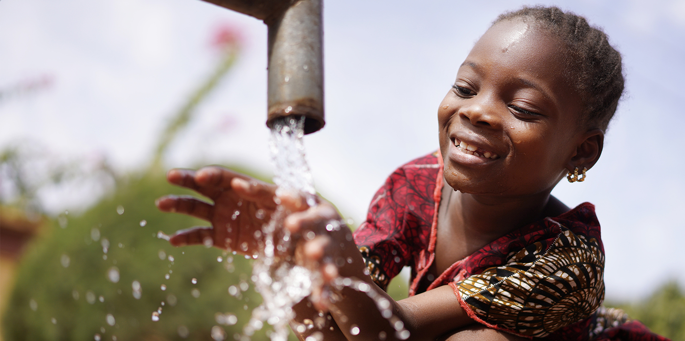 African girl putting hands in clean water