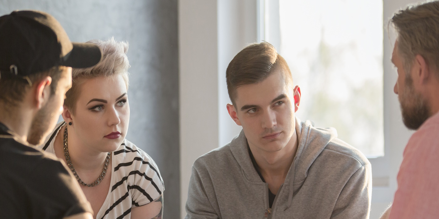 Young individuals in a group setting talking to a senior individual