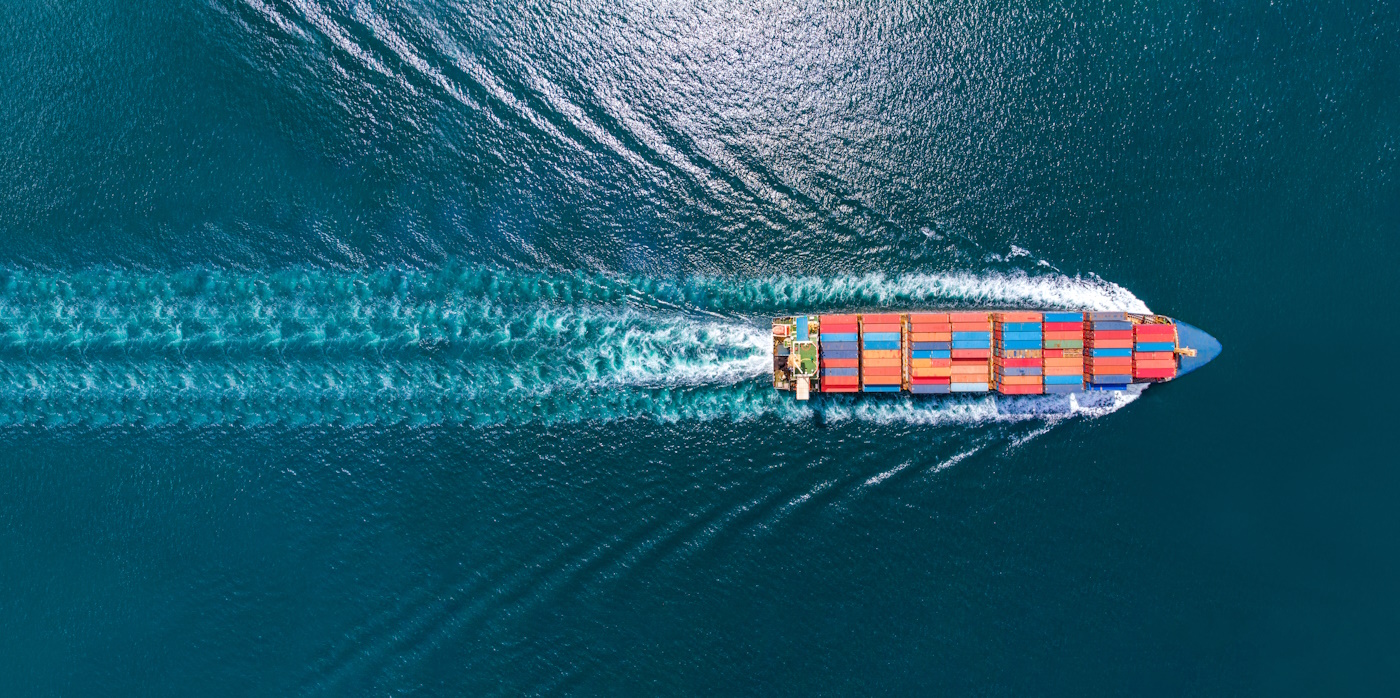 Aerial top view of cargo maritime ship with contrail in the ocean ship carrying container and running for export concept technology freight shipping